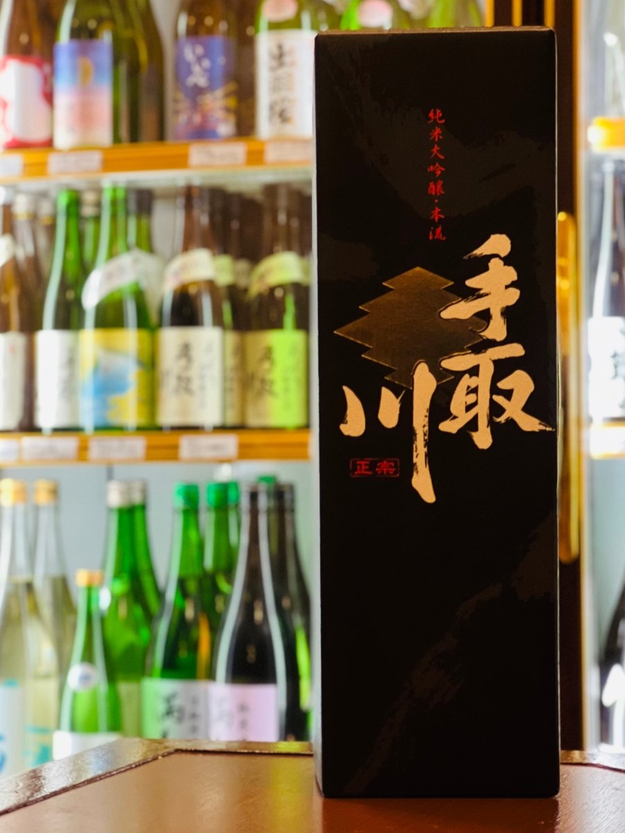 手取川 純米大吟醸 本流 化粧箱 正面デザイン。金色の手取川ロゴが入った黒いギフト箱で、日本酒の贈り物や特別な席にも使われる化粧箱。