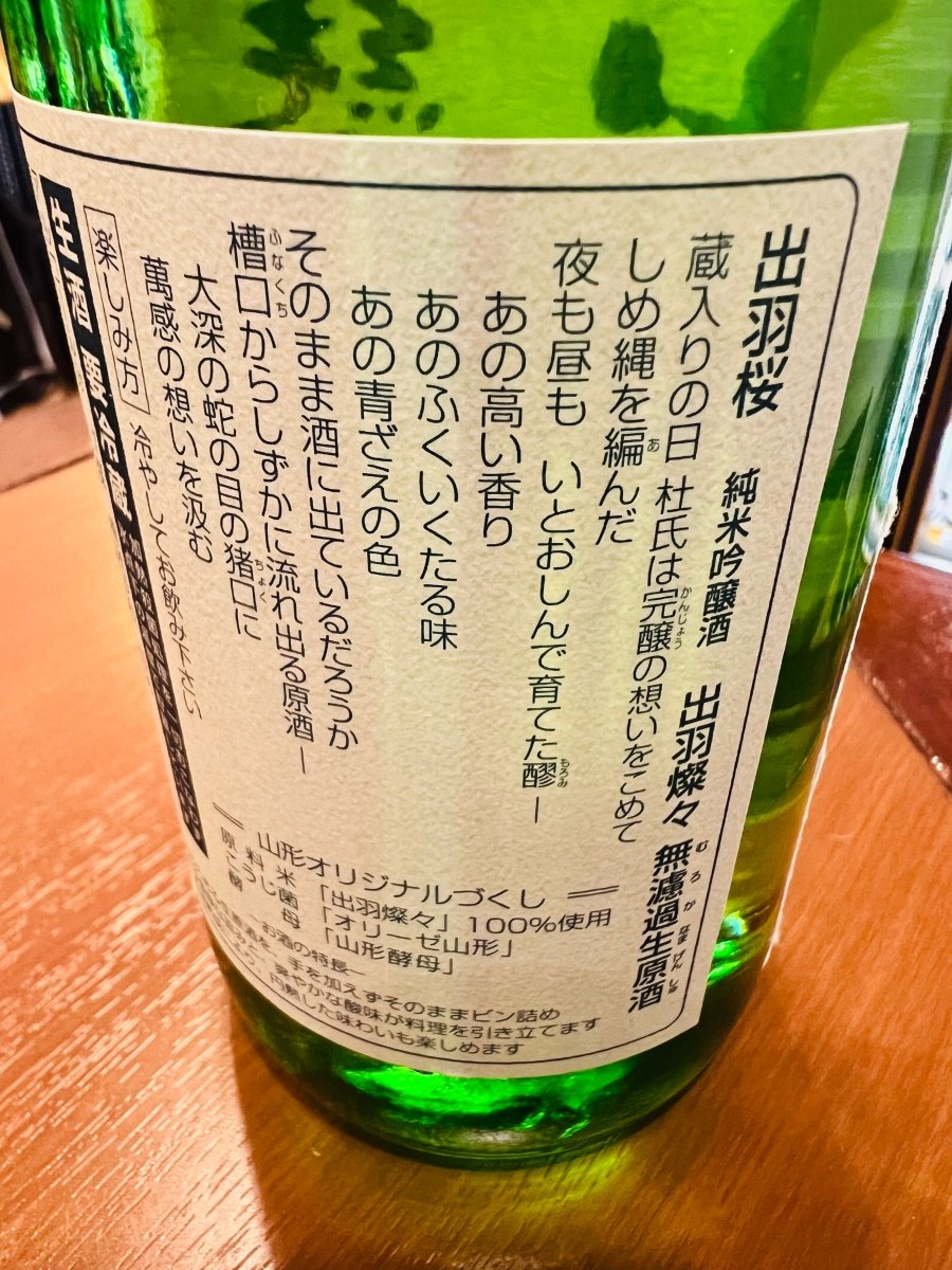 山形・出羽桜酒造「純米吟醸 出羽燦々 無濾過生原酒」の裏ラベル詳細。蔵入りの日に杜氏がしめ縄を編み、夜も昼もいとおしんで育てた醪（もろみ）への萬感の想いが綴られています。あの高い香り、ふくいくたる味、青ざえの色がそのまま酒に表れているかを問う、造り手の情熱と臨場感が伝わる叙情的なメッセージが記されたラベル画像です。