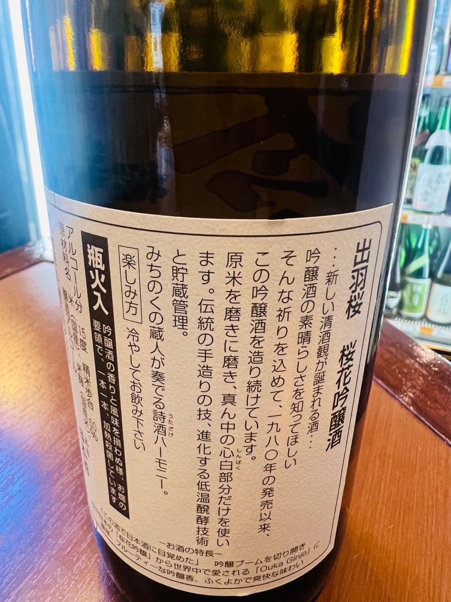 「出羽桜 桜花吟醸酒」の裏面ラベル。1980年の発売以来、吟醸酒の素晴らしさを伝えたいという祈りを込めて造り続けられている歴史が記されています。精米歩合50％まで磨き抜いた心白（しんぱく）のみを使用し、低温醗酵技術と貯蔵管理で醸された、フルーティーな吟醸香と爽快な味わいの背景を物語る製品情報の画像です。
