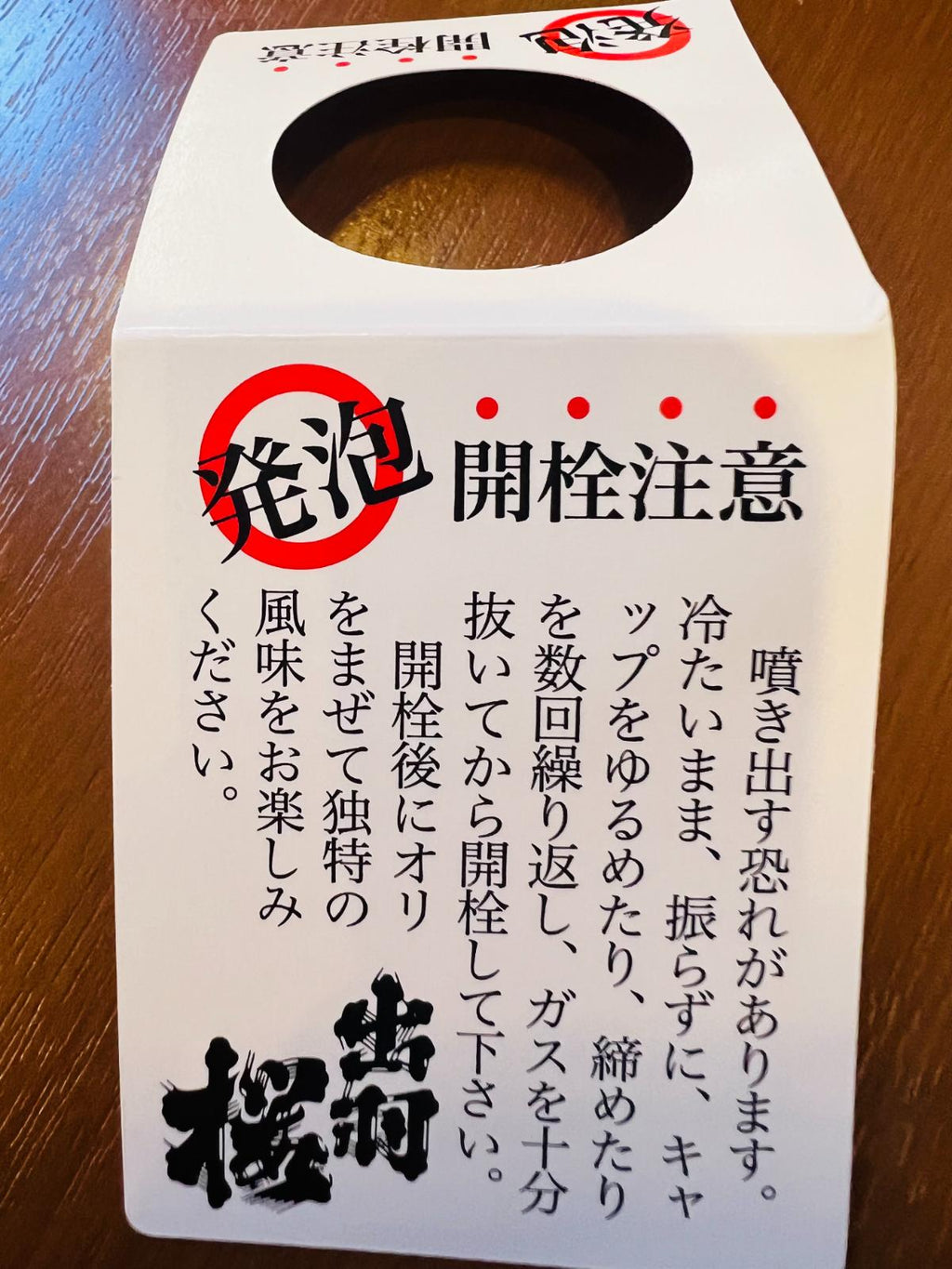 出羽桜 微発泡 吟醸にごり とび六 本生の開栓注意首掛け。噴き出し防止のため、よく冷やして振らずに開栓する注意事項を確認できるタグ。