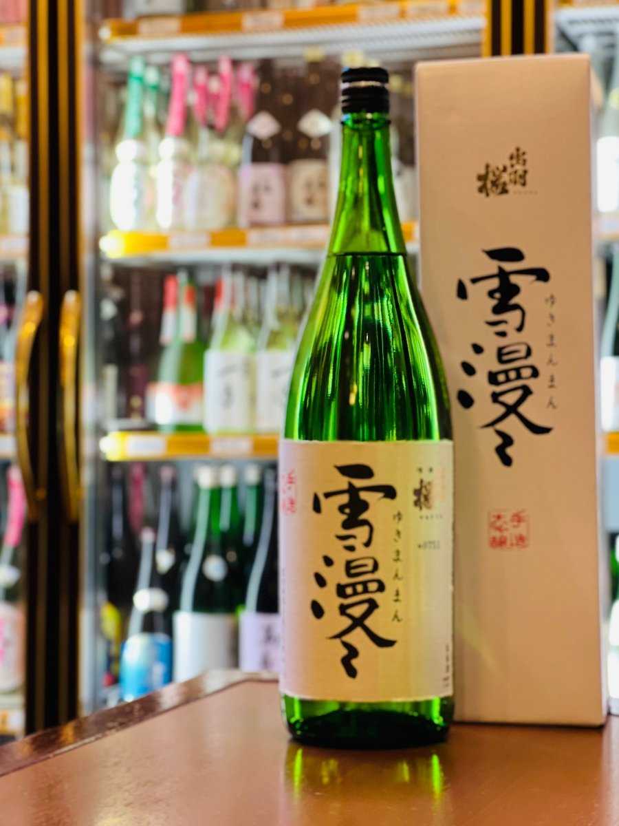 山形・出羽桜酒造の最高級ライン「大吟醸 雪漫々（ゆきまんまん）」1800ml。清涼感のある緑色のボトルと、清潔感のある白い専用化粧箱が並んでいます。厳しい基準をクリアし、低温熟成によってカスタードやバナナのような円熟した香りを引き出した、出羽桜が誇る「美しい熟成」の象徴。おせちや鴨ロース、うなぎなど、特別な日の贅沢な食卓を彩る、風格ある佇まいのギフトです。
