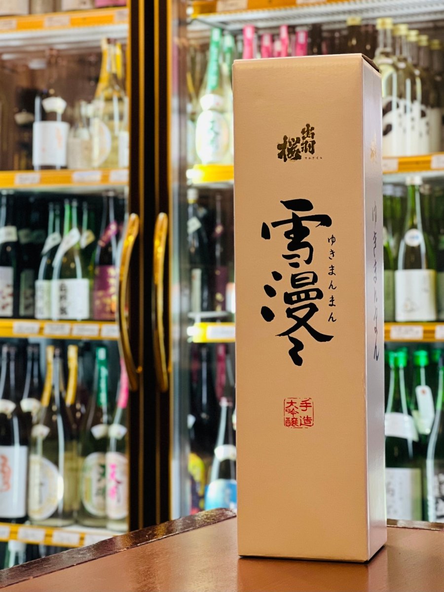 山形・出羽桜酒造の最高級大吟醸「雪漫々（ゆきまんまん）」1800ml専用の化粧箱。清潔感のある白地に、力強い筆文字で記された「雪漫々」のロゴと、手造り・大吟醸であることを示す赤い落款が美しく映えます。厳しい基準をクリアした大吟醸を低温熟成させた、カスタードのように円熟した味わいを包むにふさわしい、風格と高級感を兼ね備えたパッケージです。