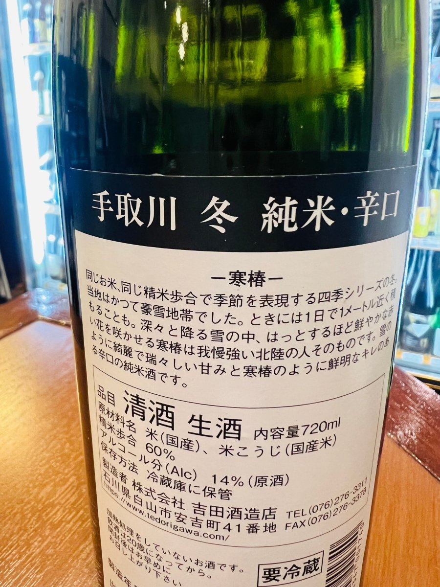 石川・吉田酒造店「手取川 冬 純米・辛口 ―寒椿―」の裏ラベル詳細。同じお米と精米歩合で季節を表現する「四季シリーズ」の冬篇です。豪雪地帯で鮮やかに花を咲かせる寒椿を、我慢強い北陸の人になぞらえたメッセージが記されています。雪のような綺麗で瑞々しい甘みと、寒椿のように鮮明なキレを目指した、蔵元の想いが伝わる画像です。