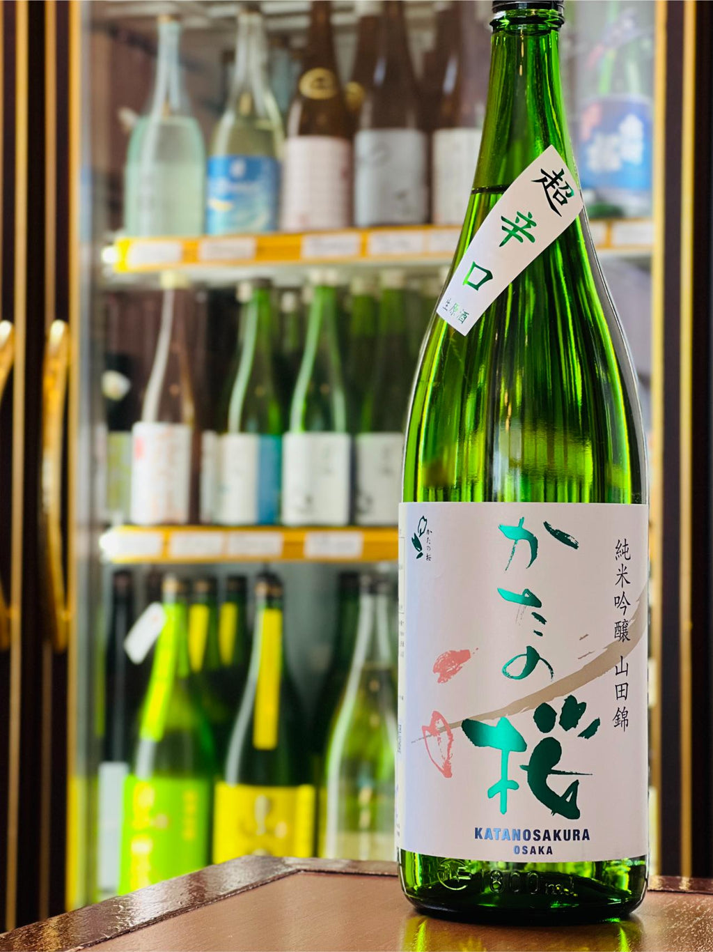 かたの桜 純米吟醸 超辛口 生原酒 1800ml。大阪府交野市・山野酒造が兵庫県産山田錦を100％使用し、58％まで磨いて醸す純米吟醸の生原酒。穏やかな香りと、超辛口らしいキレの中にしっかりとした旨味を感じる。コスパに優れた一升瓶サイズ。