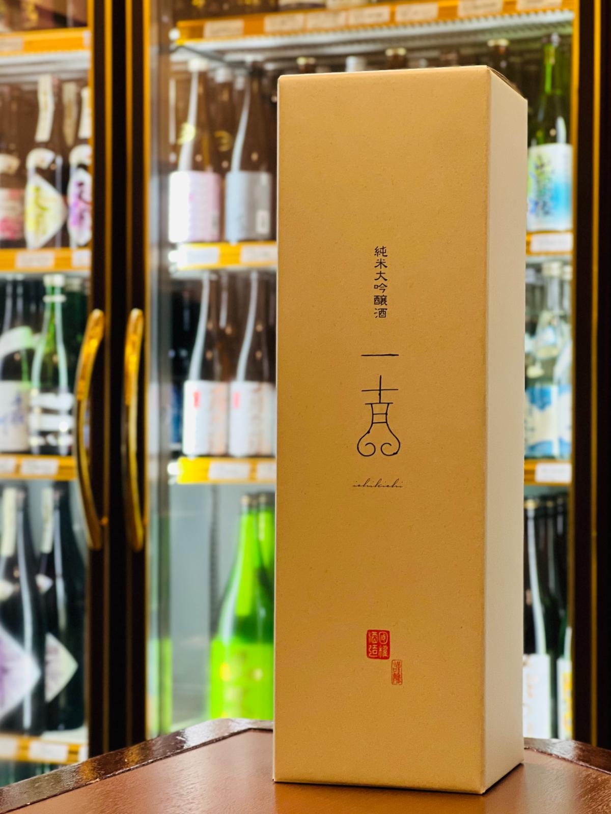 「国権 純米大吟醸 一吉 1800ml」の専用化粧箱。清潔感のある白地に、モダンにデザインされた「一吉」のロゴと「ichikichi」の英字が縦に並ぶ、洗練されたパッケージです。箱の下部には赤い落款風の印が添えられ、ハレの日の贈り物にふさわしい上品な佇まい。桃やメロンを思わせる瑞々しい香りを包み込む、国権酒造らしい「凛とした」印象を与えるギフトボックス。