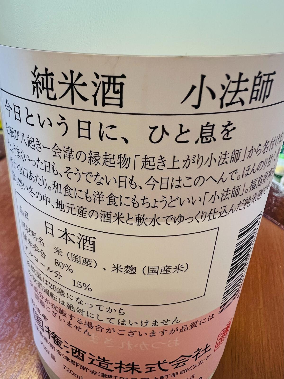 国権 純米酒 小法師の裏面ラベル接写。「今日という日に、ひと息を」の言葉と、会津の縁起物「起き上がり小法師」にちなむ商品コンセプトを記載。精米歩合80％、アルコール15％などのスペックも確認できる。