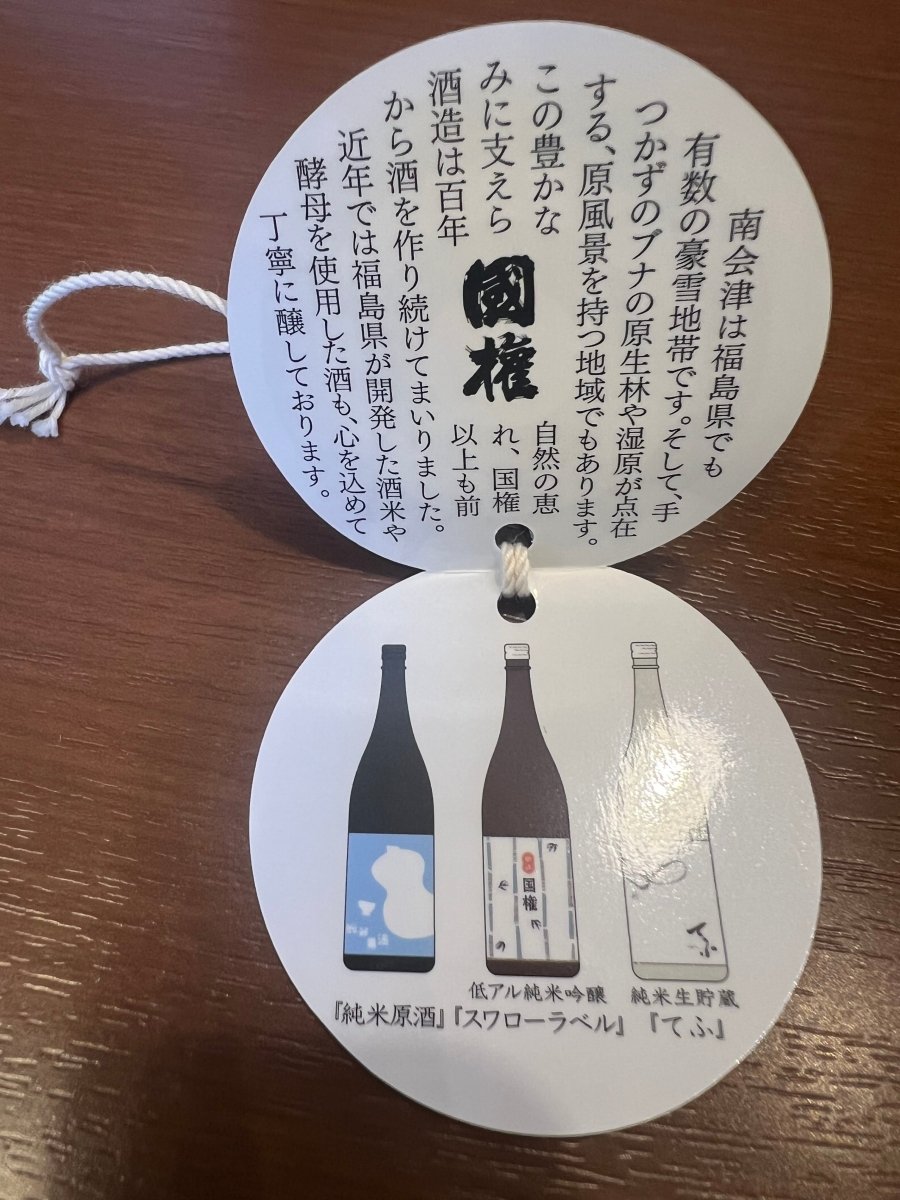 国権酒造の酒蔵紹介と福島の気候・自然のう様子・代表的な商品ラインナップが記された丸型の首掛けタグ。