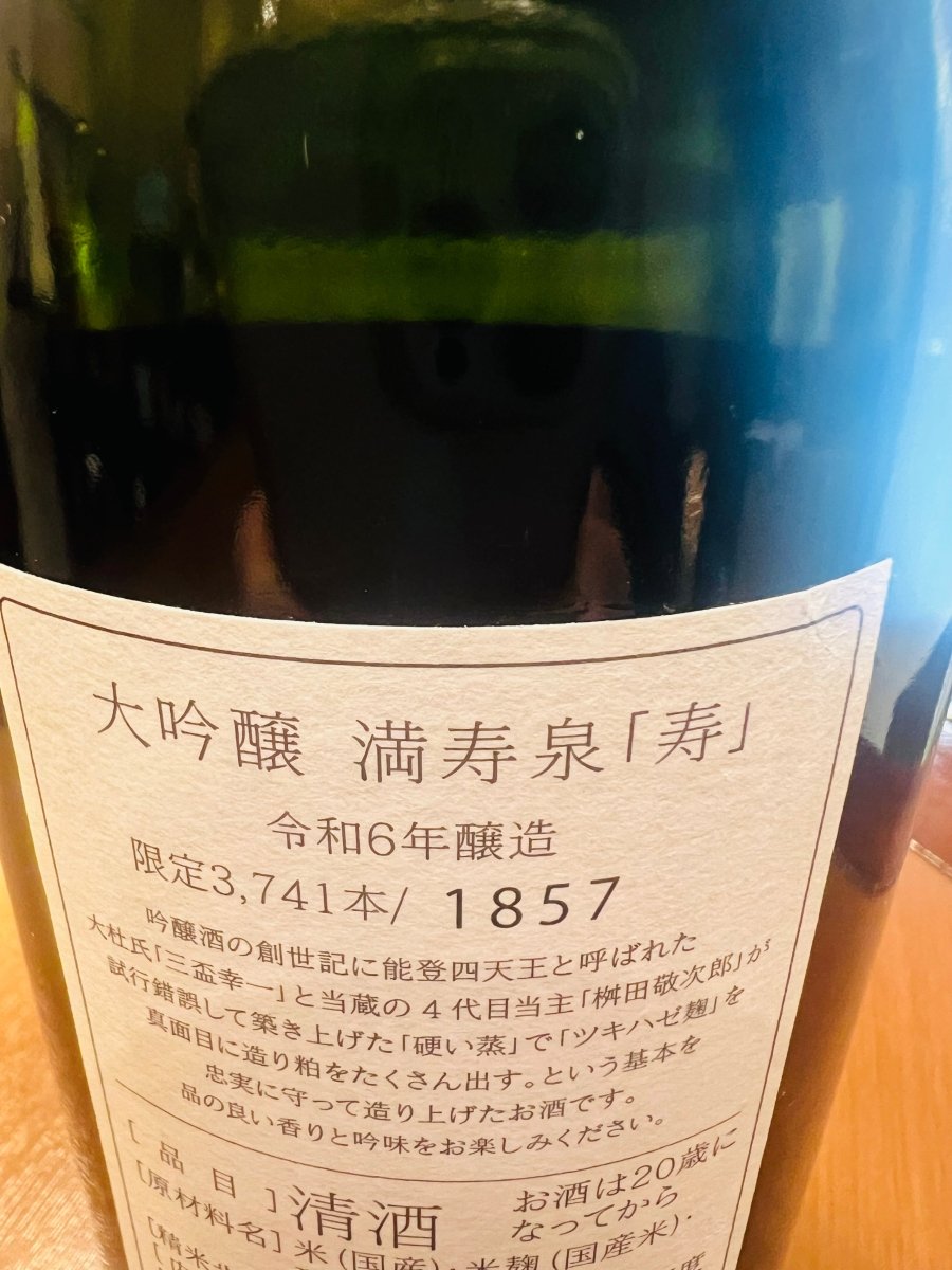 「大吟醸 満寿泉 寿」の裏面ラベル。能登四天王と称された大杜氏・三盃幸一氏と四代目当主が築き上げた、吟醸造りの原点とも言えるこだわりが記されています。「硬い蒸し」と「ツキハゼ麹」を愚直に守り、あえて粕を多く出すことで生まれる、品の良い香りと深い吟味を保証する詳細な説明文です。
