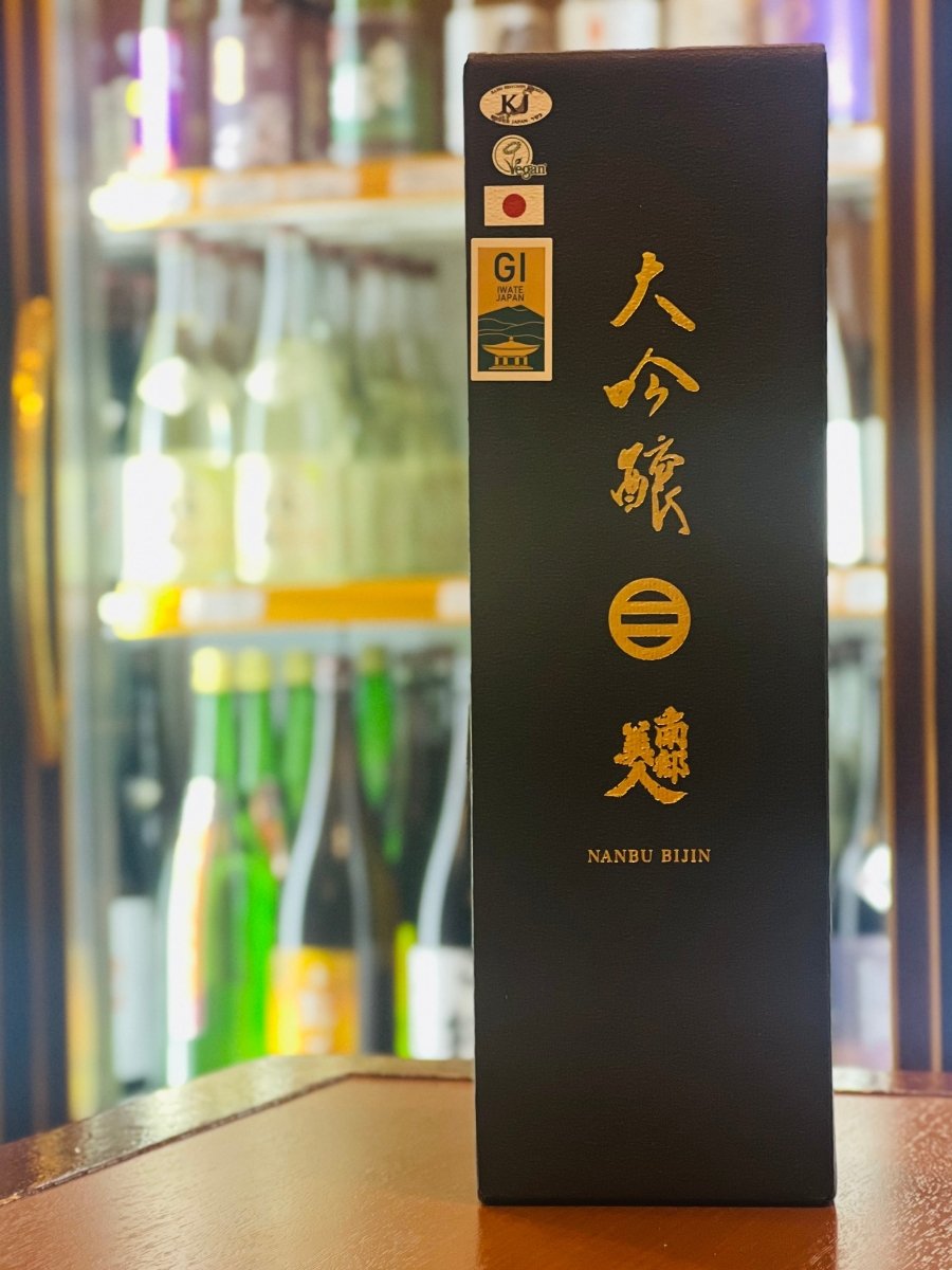 岩手・南部美人の「大吟醸」720ml専用の化粧箱。高級感あふれるマットな黒地に、黄金の輝きを放つ「大吟醸」の筆文字とブランドロゴの箔押しが目を引きます。箱の左上にはGI岩手やコーシャ認定のマークが並び、ニューヨークの一流レストランでも選ばれる世界基準の品質を物語るデザイン。カスタードやバナナのような気品ある香りを包み込む、贈り物に最適な重厚感のあるパッケージです。