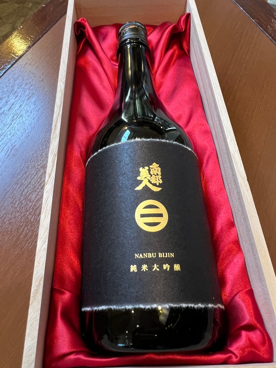 南部美人ブランドの最高峰「純米大吟醸 山田錦 35%」720ml。上質な桐箱を開けると、鮮やかな赤い布に包まれた重厚な黒いボトルが現れます。JAL国際線ファーストクラス機内酒にも選ばれた、格調高い贈り物としての魅力を伝える1枚。蜜たっぷりの林檎や熟した洋梨のような濃密でゴージャスな香りを予感させる、圧倒的な存在感を放つパッケージングです。
