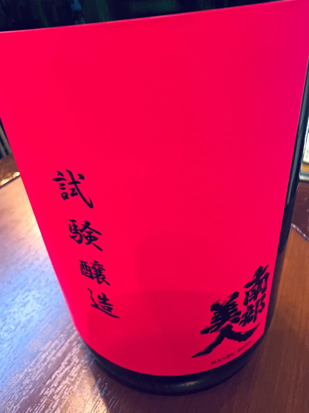 南部美人 試験醸造酒のメインラベル接写。鮮やかな蛍光ピンクのラベルに、黒文字で「試験醸造」と「南部美人」の文字を配置した印象的なデザイン。2026年発売、酒米「酒未来」を使用した限定1,200本の試験醸造酒。