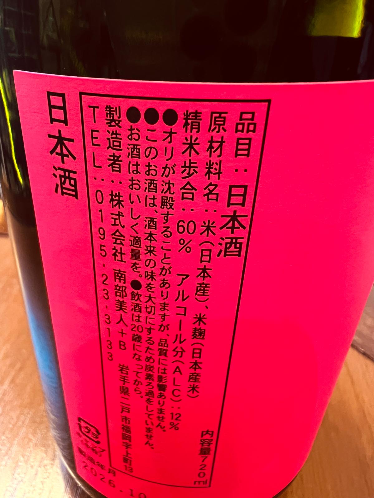 南部美人 試験醸造酒の側面ラベル接写。鮮やかな蛍光ピンクのラベルに、原材料の国産米・米麹、精米歩合60％、アルコール分12％を記載。酒米「酒未来」の味わいを大切にするため炭素ろ過を行っていない旨も説明されている。