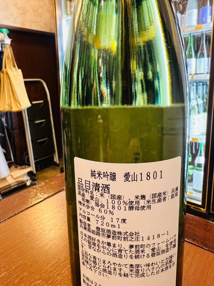 兵庫・壺坂酒造「純米吟醸 愛山1801」の裏ラベル詳細。日本酒好きが集まり、夢前町の農家・飯塚祐樹氏を中心に育てた酒米「愛山」を100％使用しています。昔ながらの酒造りを続ける壺坂酒造が、米造り八十八の手間と、丹精込めた酒造りを経て完成させた、地元の絆と情熱が詰まった日本酒であることを伝える画像です。