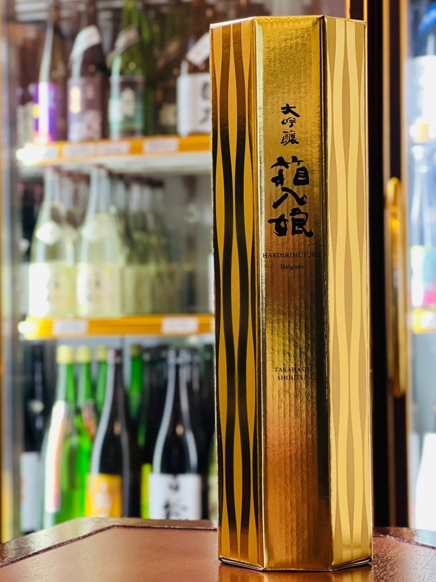 福岡・高橋商店の「繁桝 大吟醸 箱入娘」720ml専用の八角形化粧箱。地元・八女（やめ）の「八」と、末広がりの「八」をかけた縁起の良い黄金のパッケージです。光沢のあるゴールドの面に、伝統を感じさせる「箱入娘」の筆文字ロゴが美しく映えます。愛娘を育てるように技を尽くして醸された、蜜の多い高級リンゴのような香りの逸品を包む、贈答にふさわしいゴージャスな箱です。