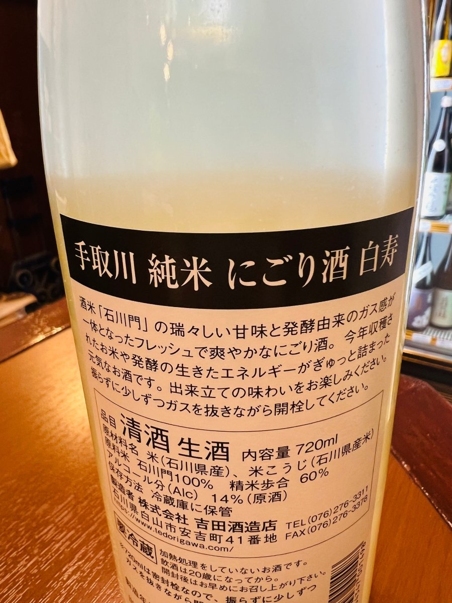 石川・吉田酒造店「手取川 純米 にごり酒 白寿（はくじゅ）」の裏ラベル詳細。酒米「石川門」の瑞々しい甘味と、発酵由来のガス感が一体となった、フレッシュで爽やかなにごり酒であることが記されています。今年収穫されたお米や、発酵の生きたエネルギーがぎゅっと詰まった「元気なお酒」の出来立ての味わいを伝える詳細画像です。