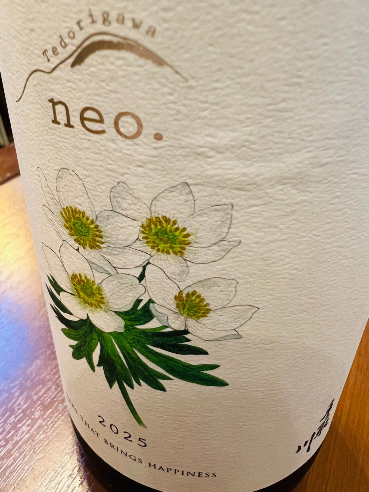 手取川 neo. 2025 SAKE THAT BRINGS HAPPINESSのラベル接写。生成り色のラベルに「neo.」「2025」「SAKE THAT BRINGS HAPPINESS」の文字と、白山の高山植物ハクサンイチゲの花が描かれている。