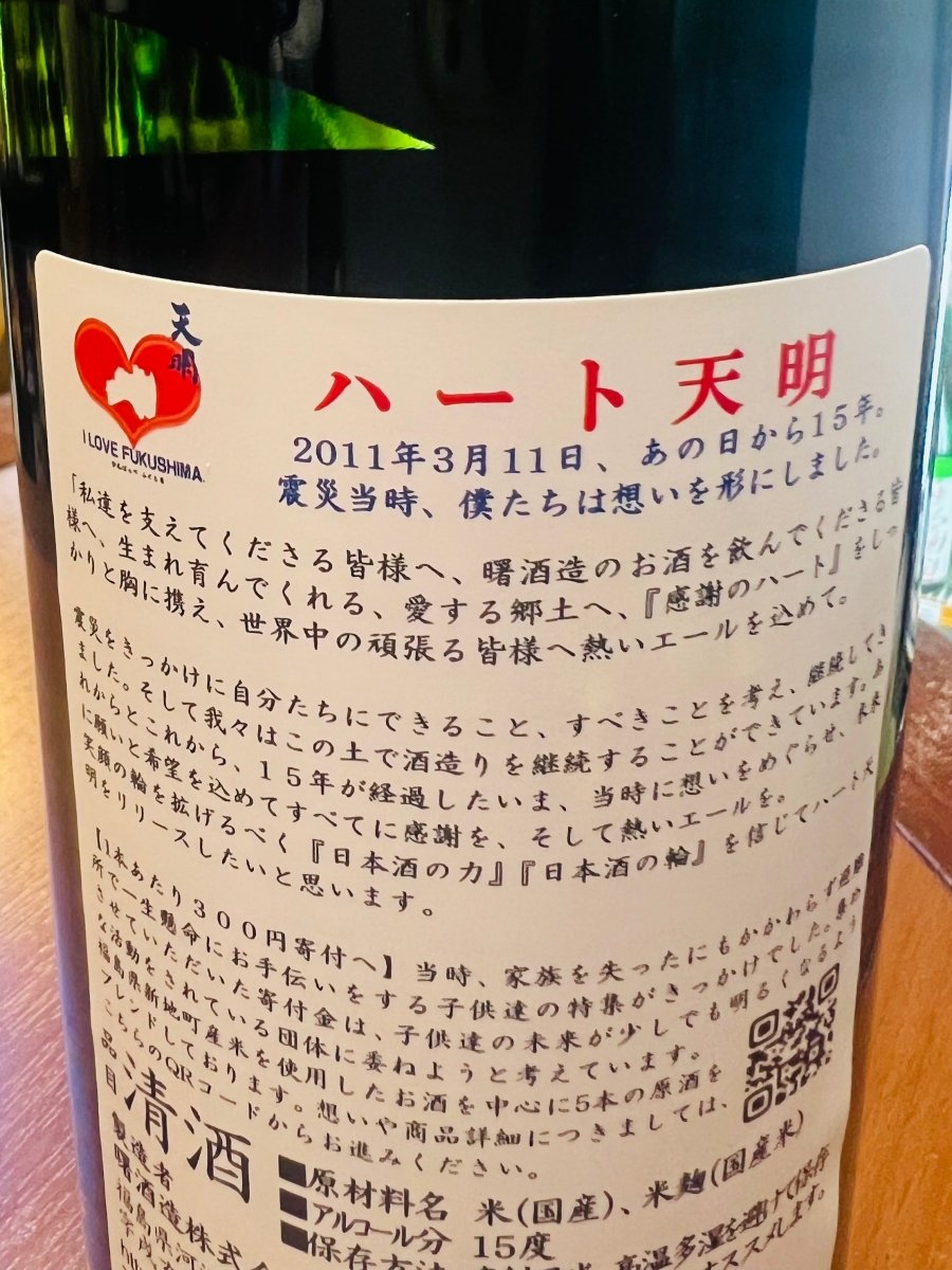 福島・曙酒造の日本酒「ハート天明」裏面ラベル。2011年の東日本大震災から15年の節目に復興支援の想いを込めて造られた経緯や寄付についての説明文が書かれている。