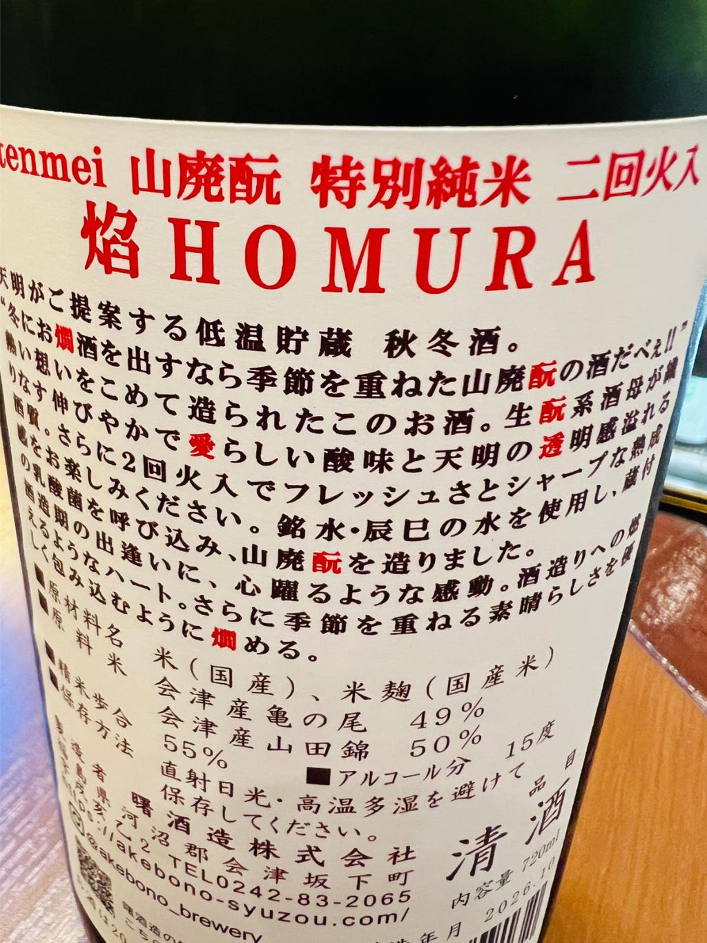 tenmei 焔 HOMURA 山廃酛 特別純米 二回火入の裏面ラベル接写。低温貯蔵の秋冬酒として、山廃酛らしい酸味と天明らしい透明感、二回火入によるフレッシュさとシャープな酒質を紹介。会津産亀の尾・会津産山田錦を使用し、精米歩合55％、アルコール15度と表示されている。