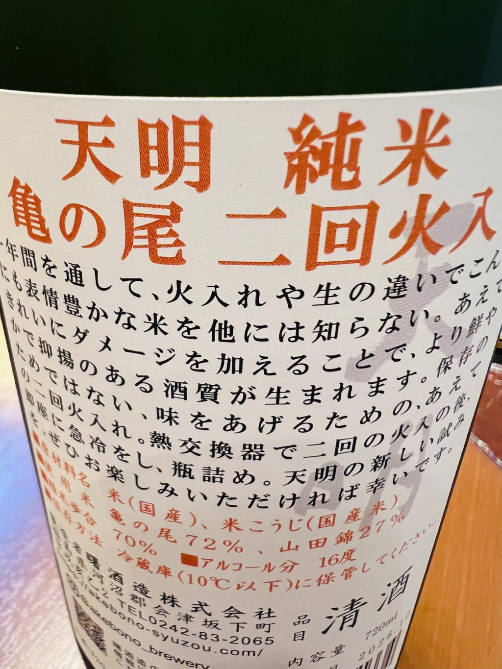 天明 純米 亀の尾 二回火入の裏面ラベル。亀の尾を使用した酒造りや二回火入れについての説明、原料米・精米歩合・アルコール分16度などの商品情報が記載された裏面ラベルの接写。