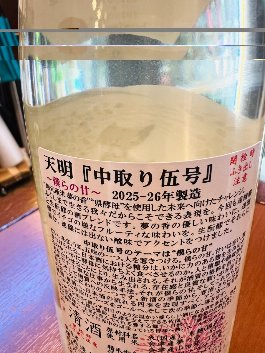 福島県・曙酒造「天明 中取り伍号」の裏ラベル。テーマは“僕らの甘”。地元産の酒米「夢の香」と「山田錦」を使用し、速醸醪と生酛醪をブレンド。イチゴのようなフルーティーさと、生酛由来の酸味が共存する味わいの設計が詳しく記載されています。「新酒から夏酒へ導くアンカー」としての想いや、生ハム、串カツ、チャーシューなどのお勧めのアテ、精米歩合やアルコール度数などの詳細スペックも網羅されています。
