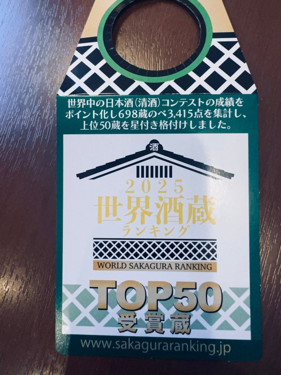 萩野酒造が「2025 世界酒蔵ランキング WORLD SAKAGURA RANKING TOP50」の受賞を記念したボトル首掛け。世界中の日本酒コンテストの成績をポイント化し、698蔵の中から上位50蔵として星付き格付けされた証です。白地に蔵のデザインと金色の文字が施された、信頼と実績を象徴する販促ラベル。贈り物や特別な1本を選ぶ際の、確かな品質の目安となる受賞記念の接写画像です。