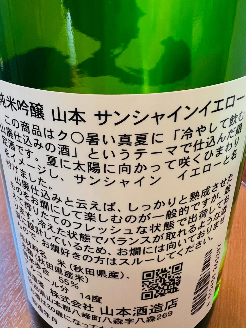 山本 純米吟醸 サンシャインイエローの裏面ラベル。秋田県八峰町・山本酒造店が秋田県産米を55％まで磨き、山廃仕込みで醸すアルコール14度の夏季限定酒。冷やして飲む山廃仕込みをテーマに、フレッシュな状態でバランスを整えた酒質について記載。
