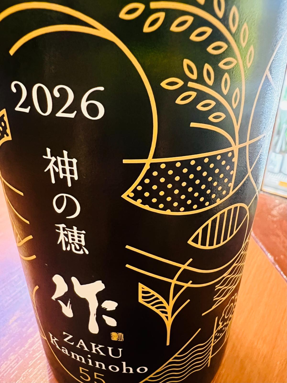 作 純米吟醸 神の穂 2026のプリント瓶デザインとロゴのアップ。「2026 神の穂」「作 ZAKU Kaminoho 55」の文字と、稲穂や田園をモチーフにした金色の意匠が施された限定デザイン。