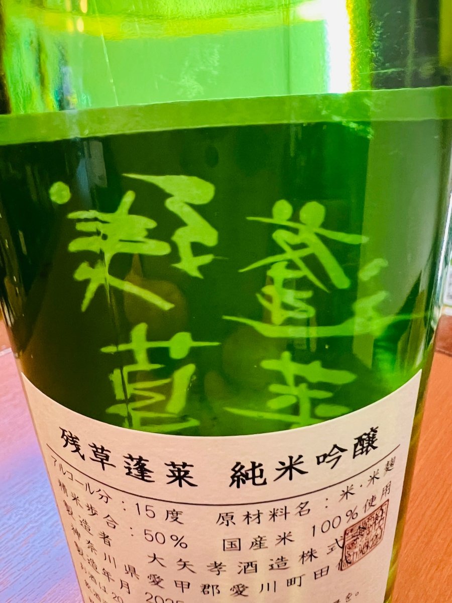 神奈川・大矢孝酒造「残草蓬莱（ざるそうほうらい）純米吟醸」のラベル詳細。緑のボトルに映える黄緑色の筆文字と、精米歩合50%、アルコール分15度といった製品スペックが記されています。原材料には国産米を100%使用。蔵元が「馥郁（ふくいく）たる香りと爽快感のある味わい」と定義する、米の旨味を引き出しつつキレの良さを追求した、丁寧な造りと品質の証を確認できる画像です。